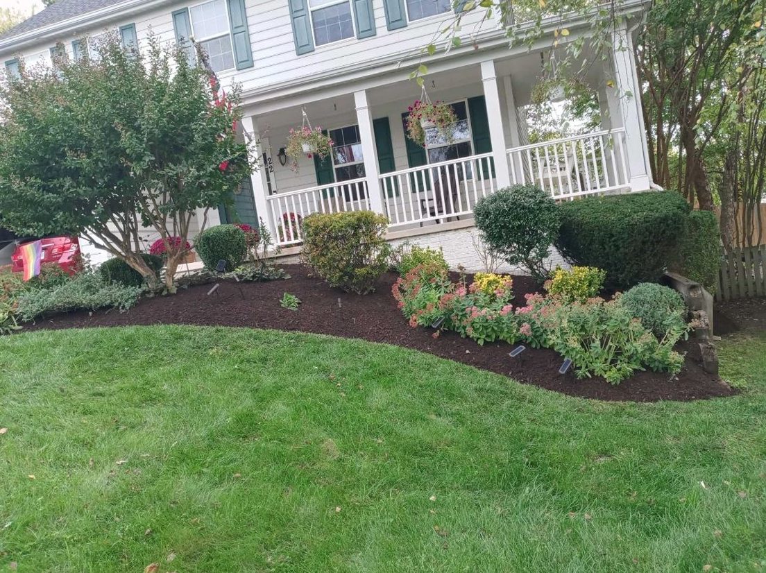 Curved mulched bed with mixed shrubs in front of a porch