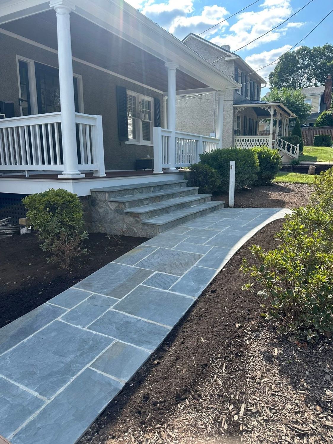 Bluestone front walk leading to stone-faced steps at a covered porch