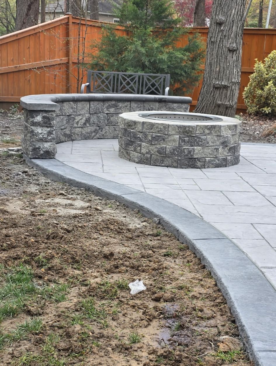 Block fire pit and curved seat wall with a stone cap on a stamped concrete patio