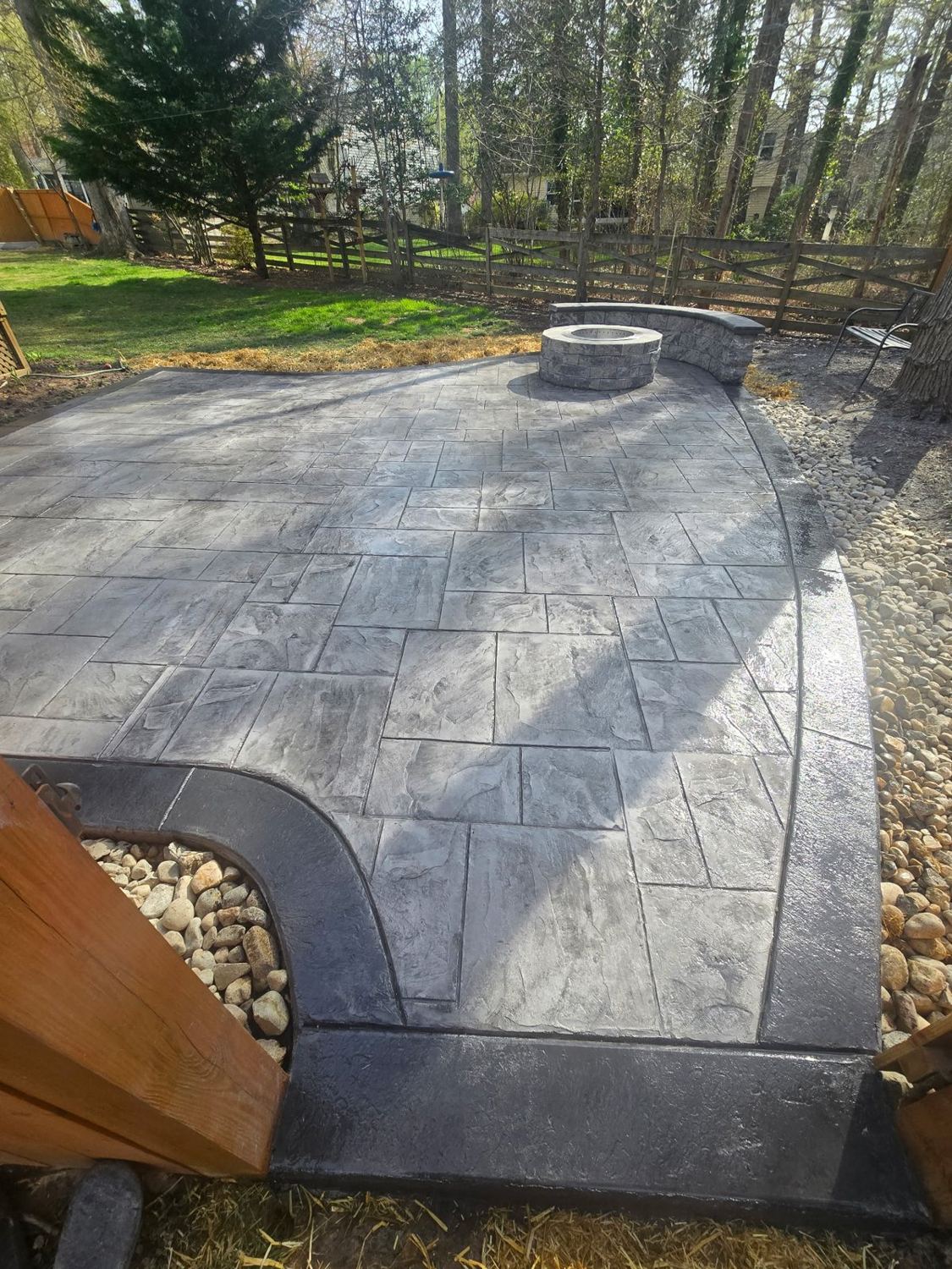 Stamped patio with a fire pit and curved seat wall at its edge