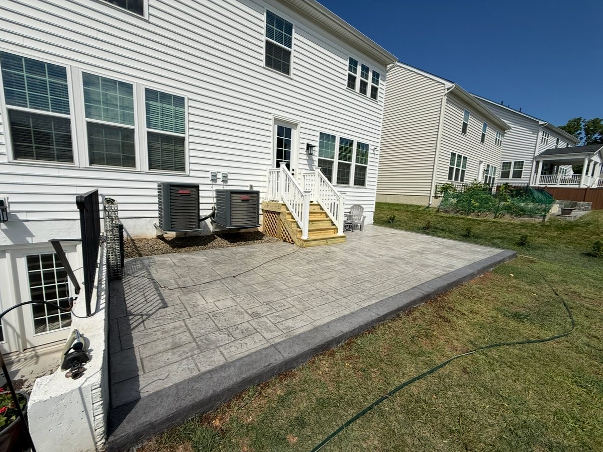 Large stamped concrete patio with a contrasting border across the back of a home